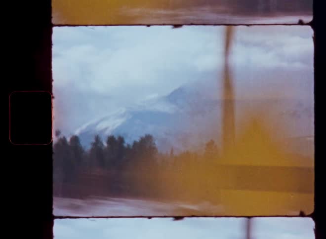 A vintage, dreamy view of a snowy mountain range and forest as seen from a fast-moving vehicle