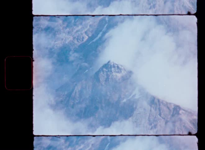 A majestic mountain peak emerges from the clouds in this authentic vintage film footage