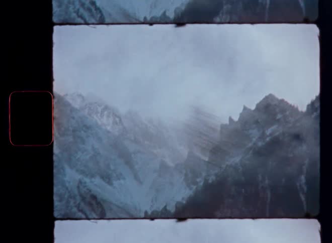 Handheld vintage Super 8 footage captures a foggy, snow-covered mountain range on a cold day