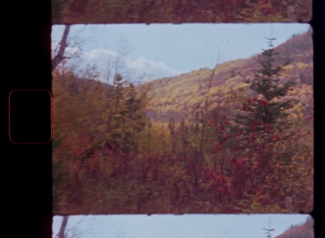 A shaky handheld vintage film shot reveals a stunning mountain landscape covered in colorful autumn foliage
