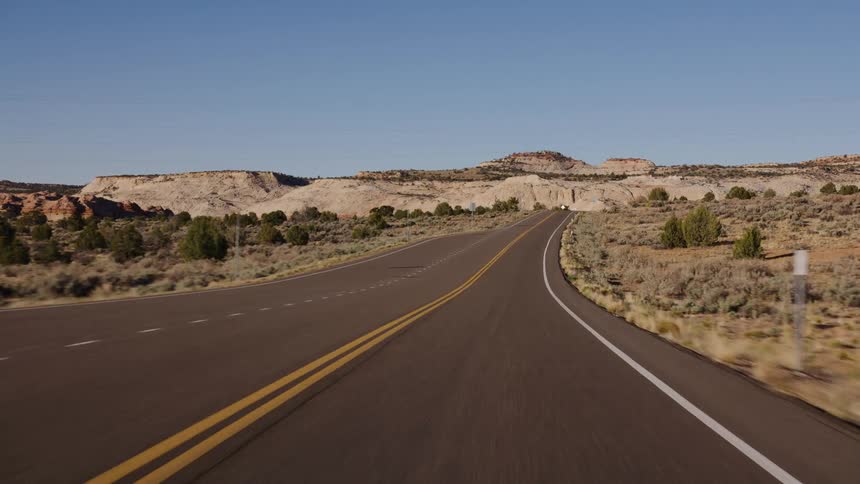 Driving point-of-view on a scenic desert highway through the canyons of Utah on a clear day