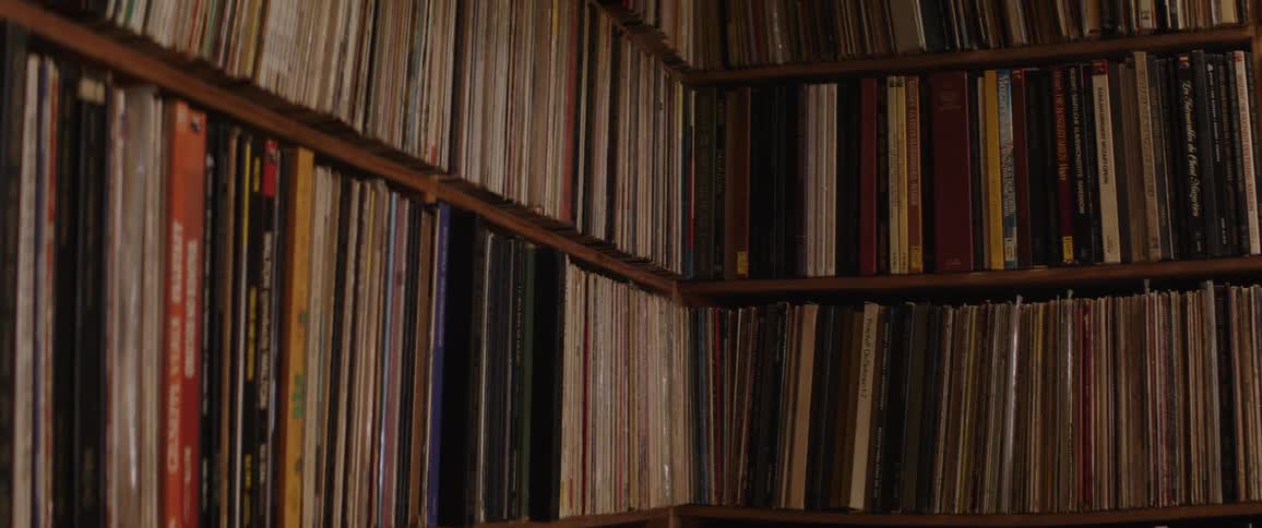 A close-up shot of a vast collection of vintage vinyl records neatly organized on wooden shelves