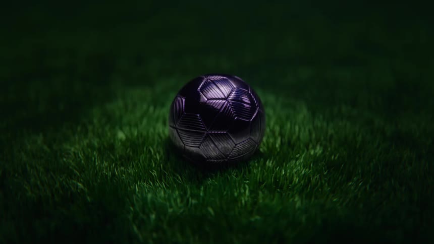 A stylized, abstract shot of a chrome soccer ball on a green field with flickering, dramatic lights