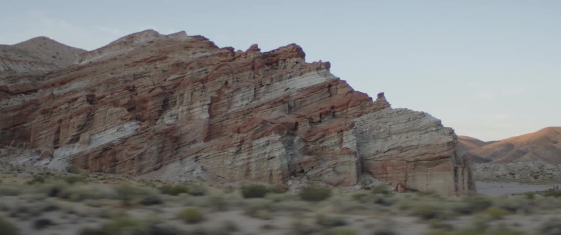 A scenic drive through a desert landscape reveals towering red and white striped rock formations