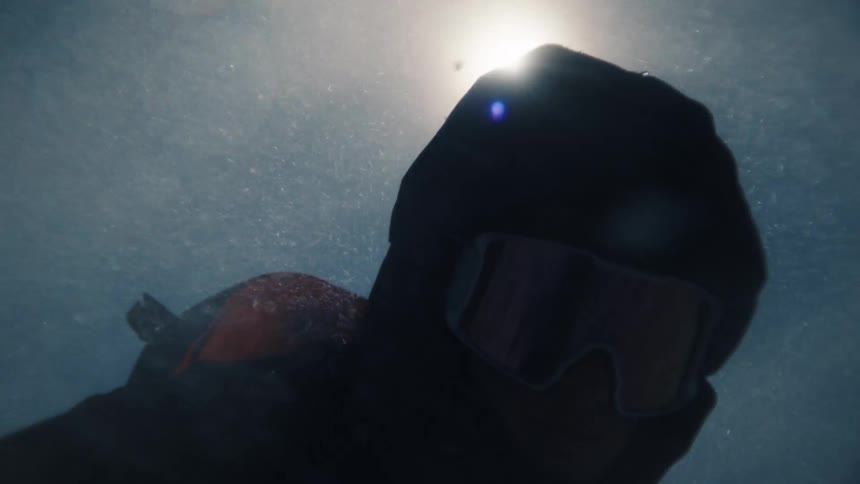 Dramatic slow-motion close-up of a climber in a balaclava and goggles facing a blizzard