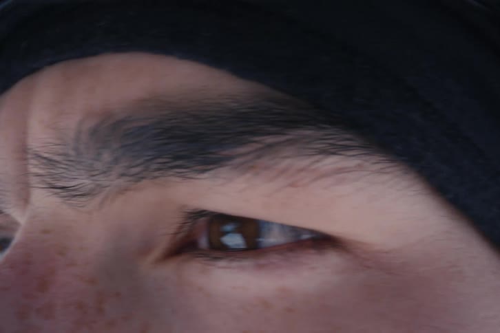 An extreme close-up of a man's focused eyes as he scans his surroundings with intensity