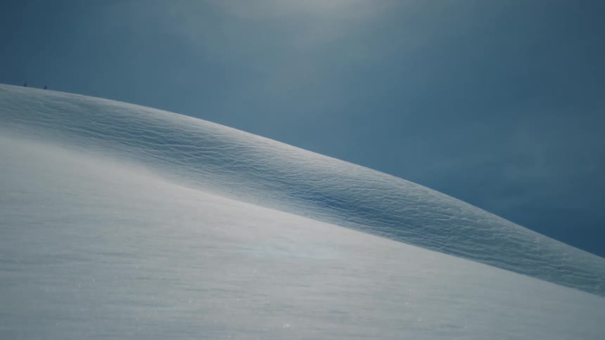 Minimalist abstract view of a pristine white snow-covered mountain ridge against a deep blue sky