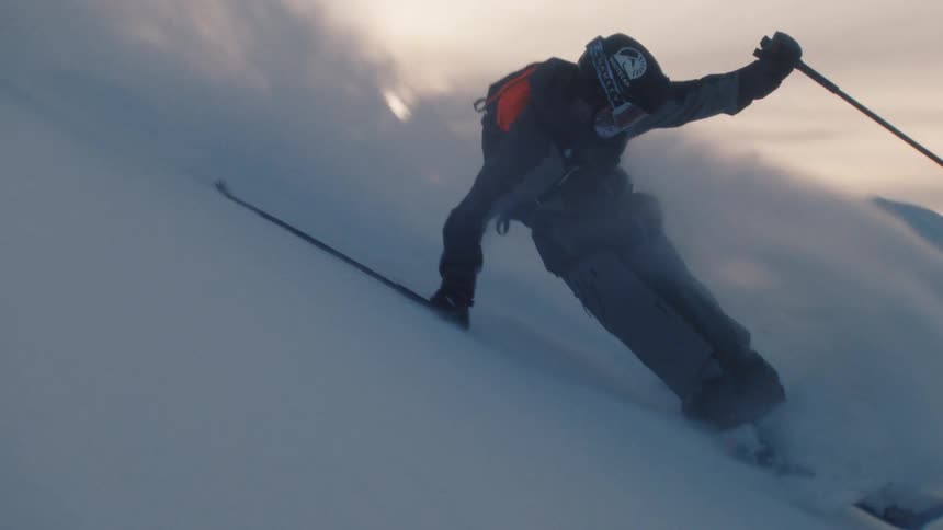 A professional skier carves through pristine powder snow on a vast mountain in stunning slow motion