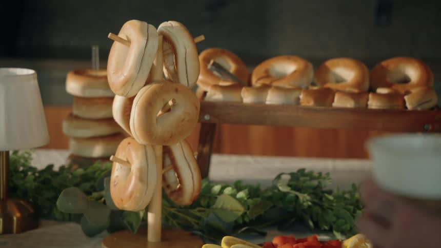 A slow-motion close-up reveals a delicious bagel bar with fresh sliced vegetables and bagels hanging on a display stand