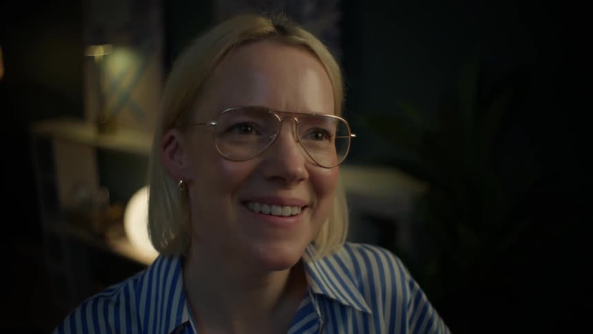 A smiling blonde woman in glasses closes her laptop, signifying the end of a productive work day at home