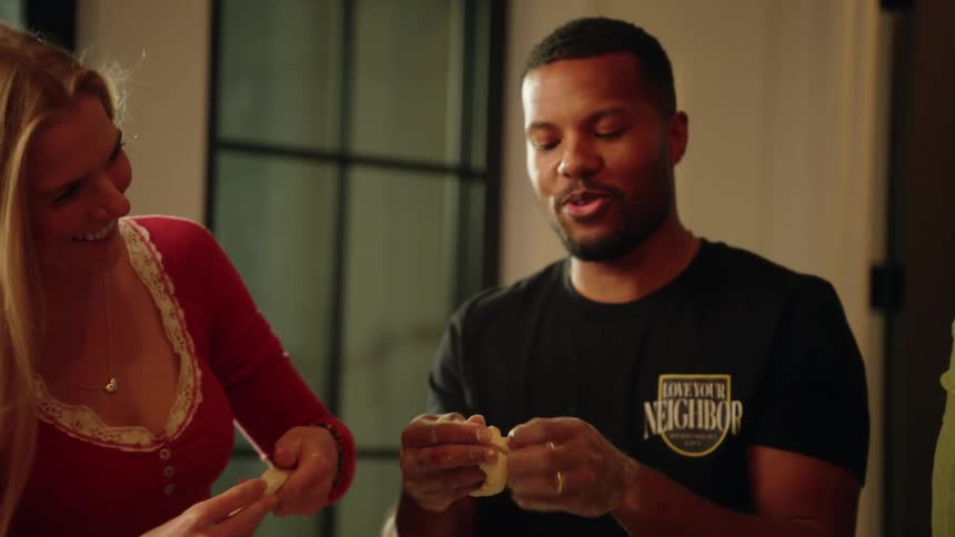 A diverse group of friends laugh and have fun while making homemade dough in slow motion