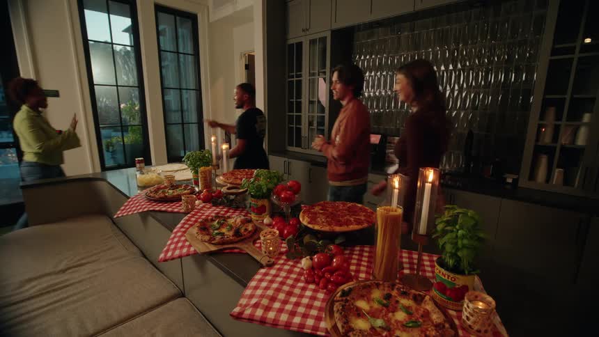 A happy host welcomes his friends as they arrive for a fun pizza party in a stylish, modern kitchen