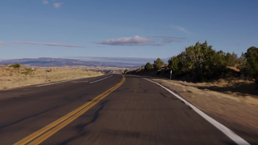 A scenic point-of-view drive along a winding rural highway through the arid landscapes of the American Southwest