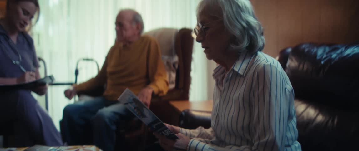 An elderly couple discusses in-home care options with a visiting nurse in their living room