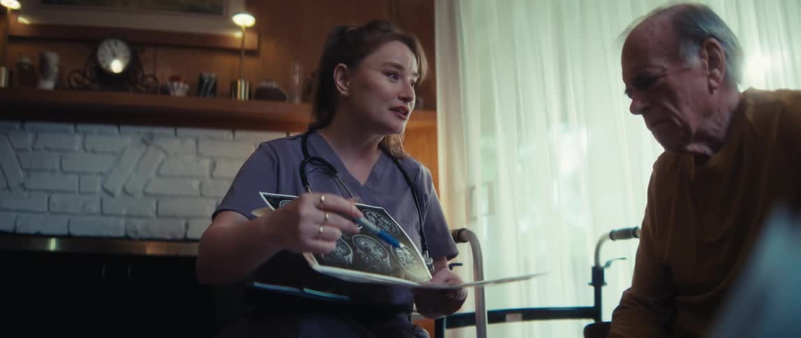 A caring female nurse discusses brain scan results with an elderly male patient during a home visit, offering a reassuring and professional explanation