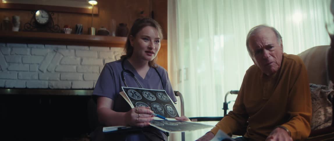 A compassionate nurse delivers hopeful news while reviewing a brain scan with an elderly couple in their home