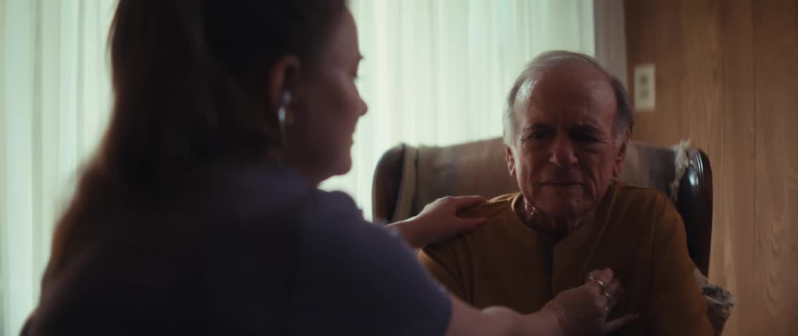 A dedicated nurse carefully listens to an elderly man's heartbeat with a stethoscope during an in-home medical visit
