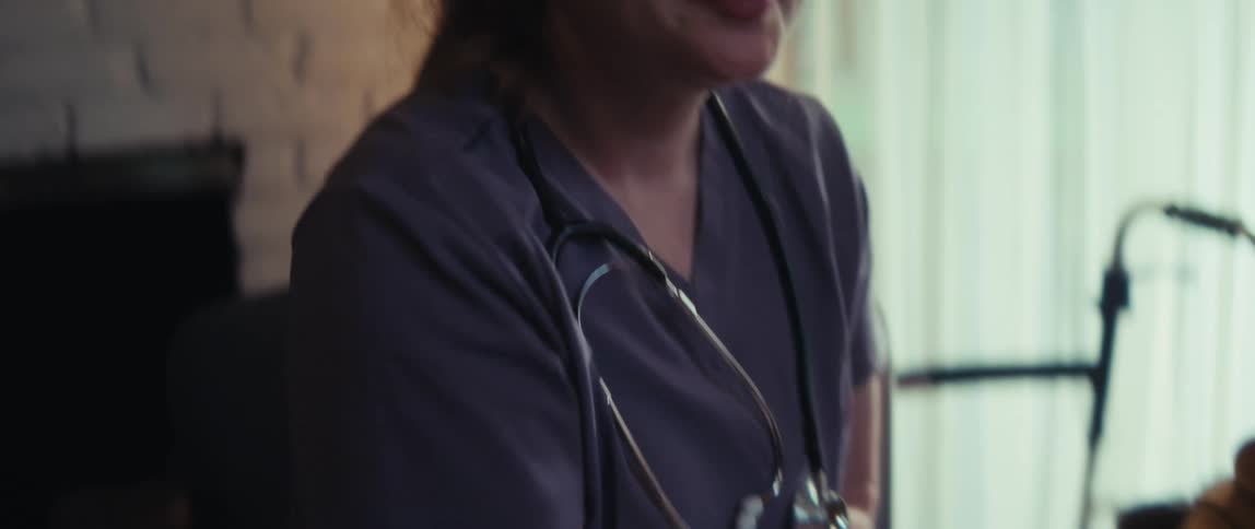 A friendly female healthcare worker shakes her patient's hand with a warm and reassuring smile during a home visit