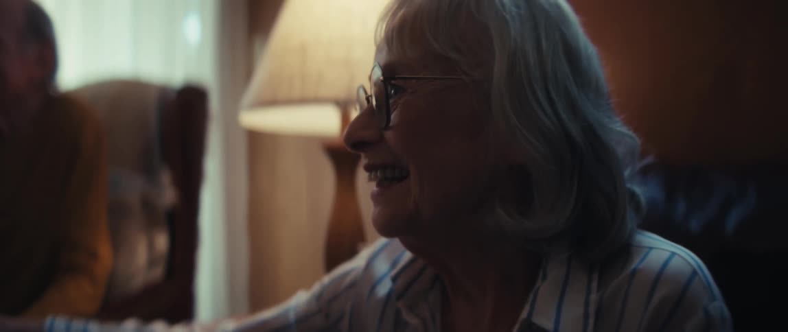 A compassionate home healthcare nurse provides comfort and support to a smiling elderly couple during a home visit, shaking their hands reassuringly