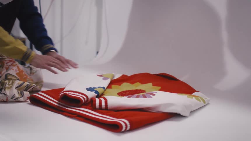 A photographer and stylist collaborate in a studio, carefully arranging and shooting colorful jackets for a product photoshoot