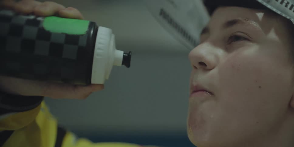A young athlete rehydrates by drinking water from a sports bottle in a slow-motion close-up