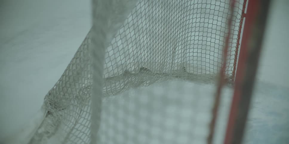 Close-up slow-motion footage of a hockey puck hitting the net and scoring a goal