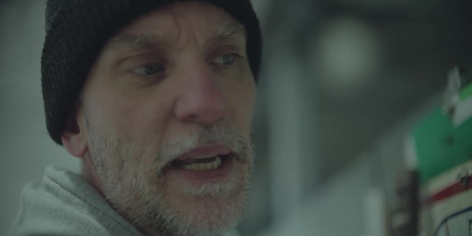 Slow-motion close-up shot of a man in a black beanie speaking with a serious expression