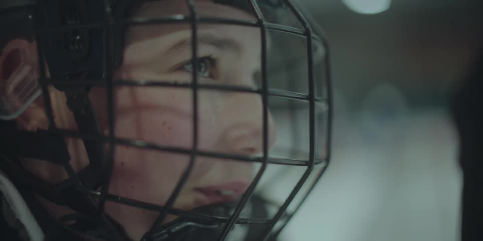 The face of a young hockey player in a helmet transitions from intense focus to a joyful smile