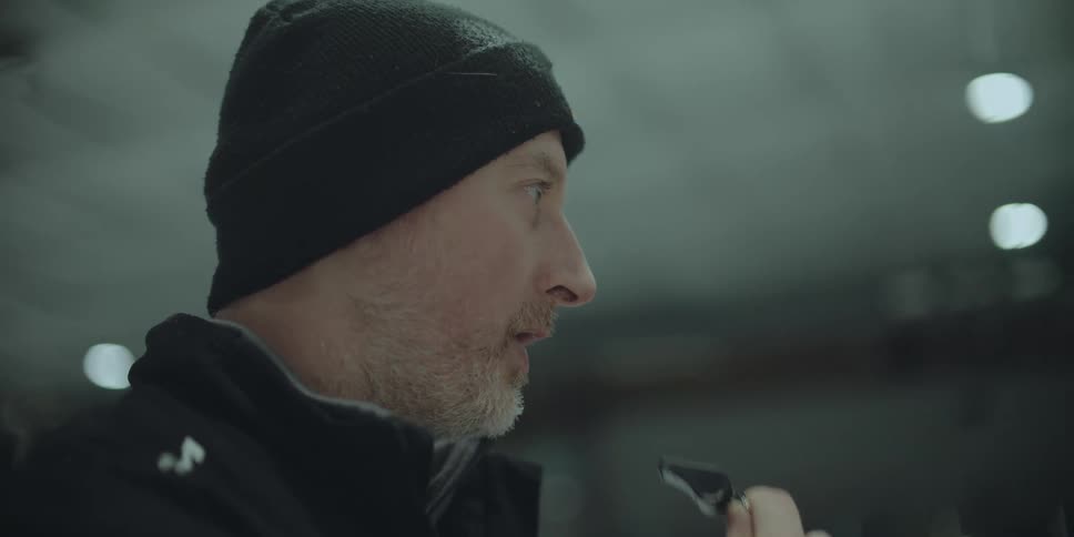 A dramatic slow-motion close-up of a male coach blowing a whistle in an arena