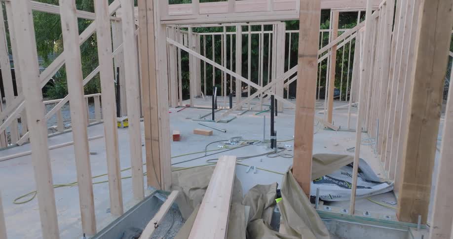 Slow pull-back reveal through the wooden framing of a new residential home during the initial construction phase