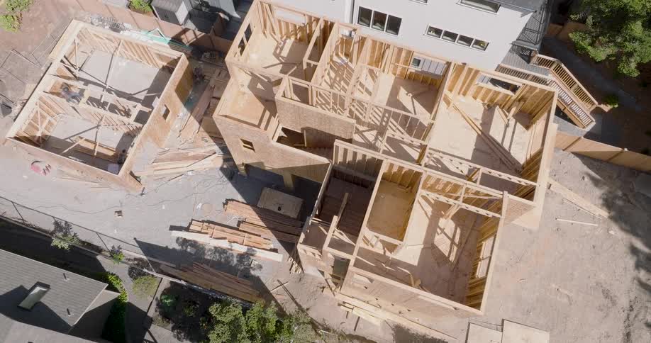 Workers build out the wood frame of a brand new home under construction