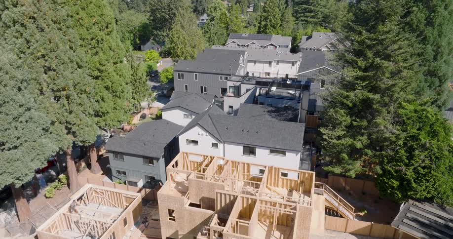 Brand new modern homes rise between the tall trees of a quiet suburban neighborhood