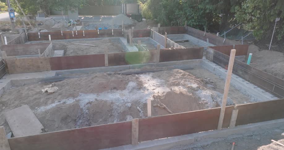 Low skim over a new residential construction site, revealing the entire foundation with wooden forms and rebar cages ready for concrete