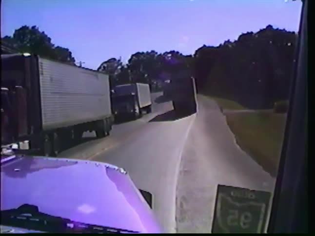 Point-of-view footage from a purple semi-truck driving past a convoy of other trucks on a rural Ohio highway on a sunny day