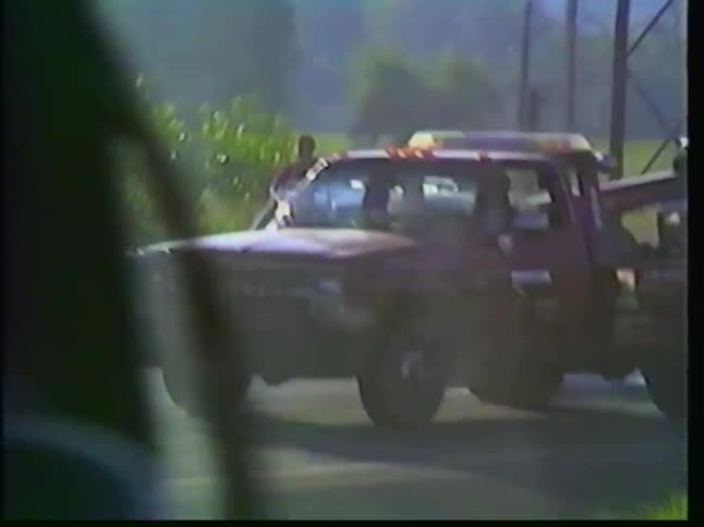 Vintage VHS footage captures the aftermath of a car accident on a highway with emergency services and police on the scene