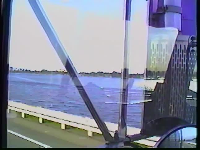 Vintage VHS footage from a truck driver's perspective shows a sunny day commute on a highway running alongside a wide river