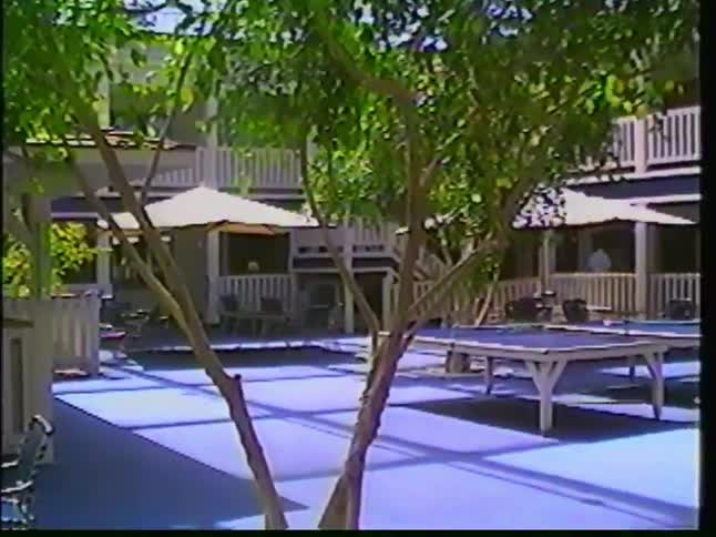 A quiet hotel recreation area with a pool and game tables, shot on vintage VHS