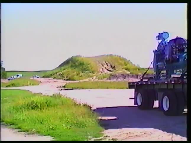 Vintage footage shows a custom purple semi-truck transporting heavy industrial machinery to a rural site