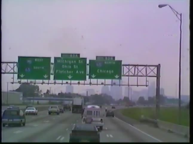 Driver's point of view footage from the 1990s shows traffic on a hazy highway approaching Indianapolis, Indiana