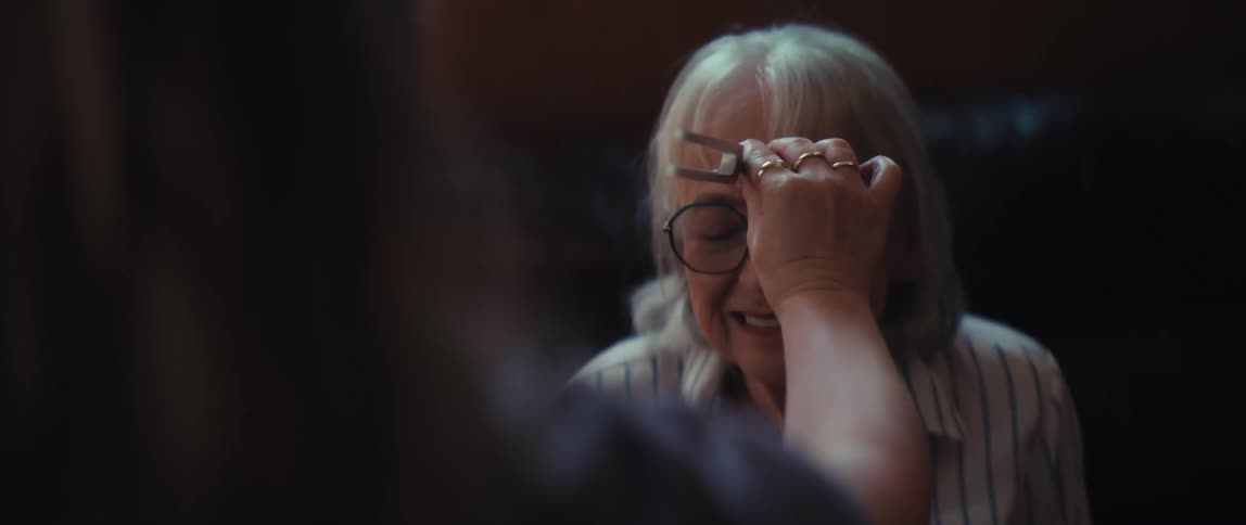 An elderly woman experiences calming sound healing therapy as a practitioner places a vibrating tuning fork on her forehead