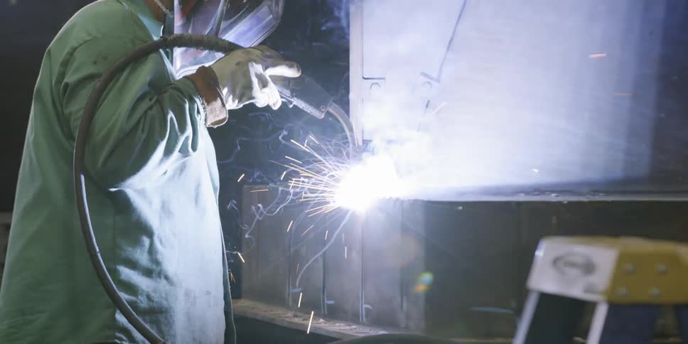 Sparks fly around a working welder