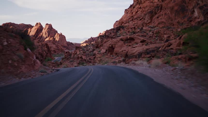 A scenic point-of-view drive along a winding road through a majestic red rock canyon at sunrise