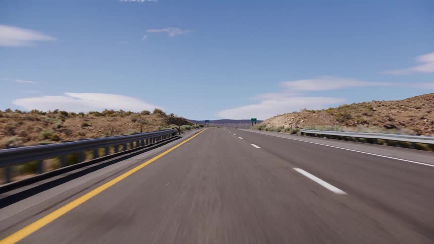 Driving point-of-view on a desolate desert highway on a bright sunny day