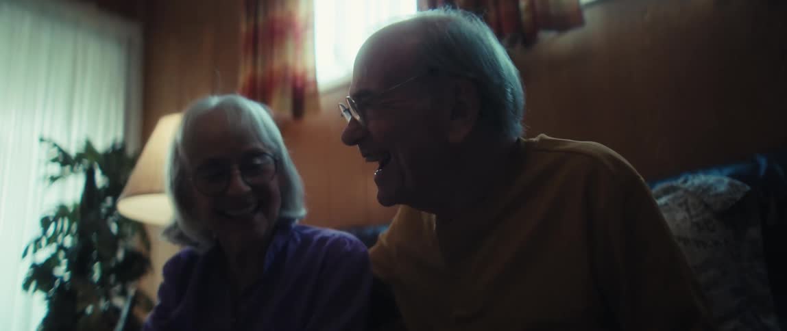 A consultant delivers positive news, bringing laughter and joy to a senior couple in their cozy home