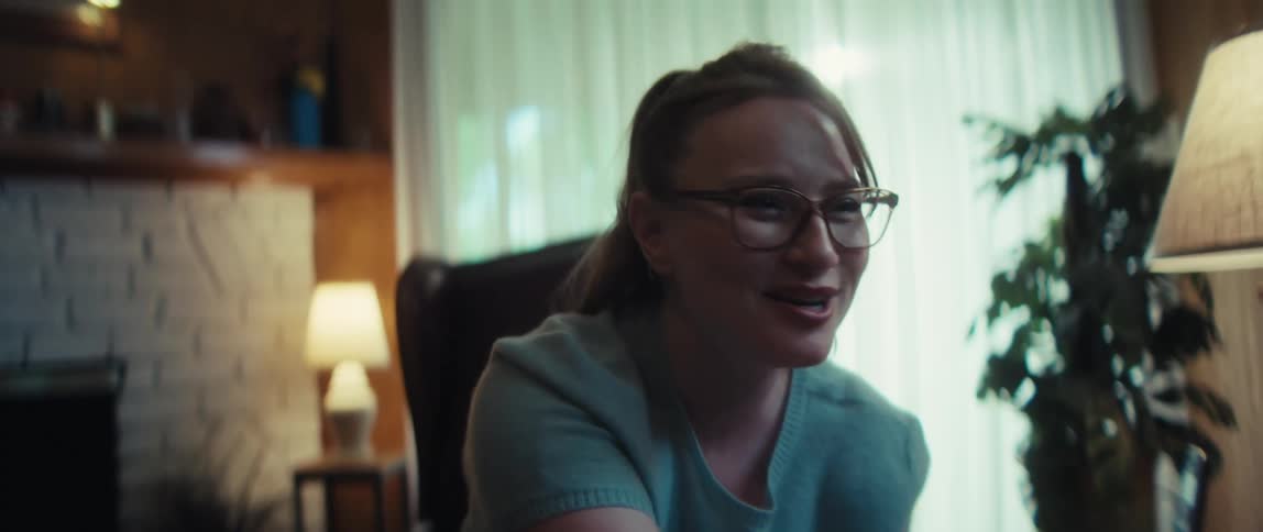 A caring young woman with glasses shares a joyful laugh during a heartfelt conversation in a warm living room