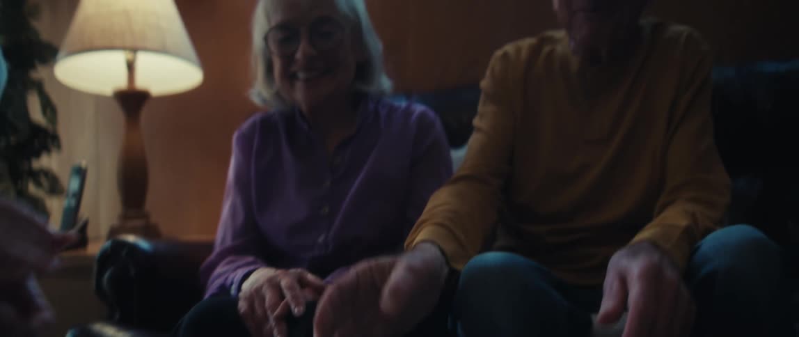 A young professional shakes hands with a smiling senior couple after presenting them with a successful financial report in their cozy living room