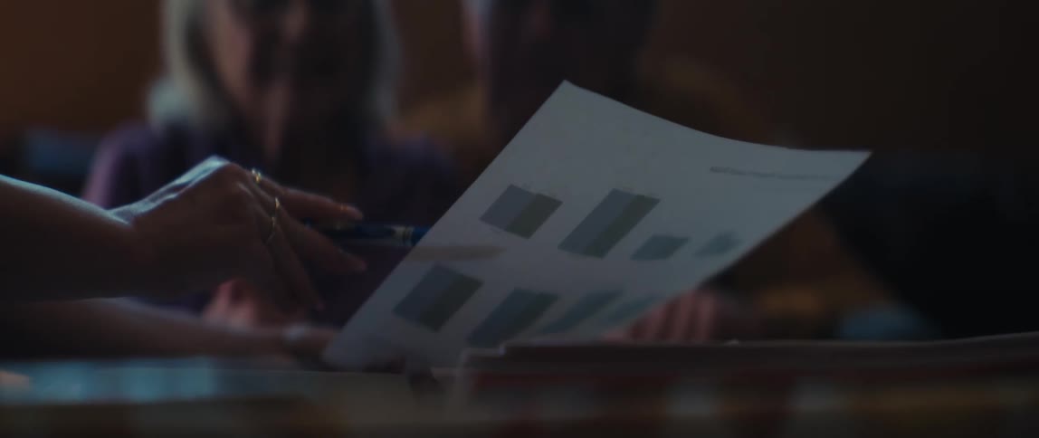 An elderly couple listens intently as a consultant reviews financial performance charts with them in slow motion