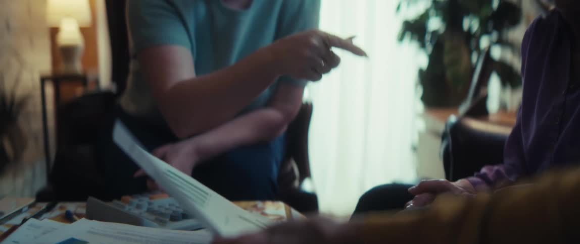 A caring female financial advisor concludes a successful consultation with an elderly couple, shaking hands in their home