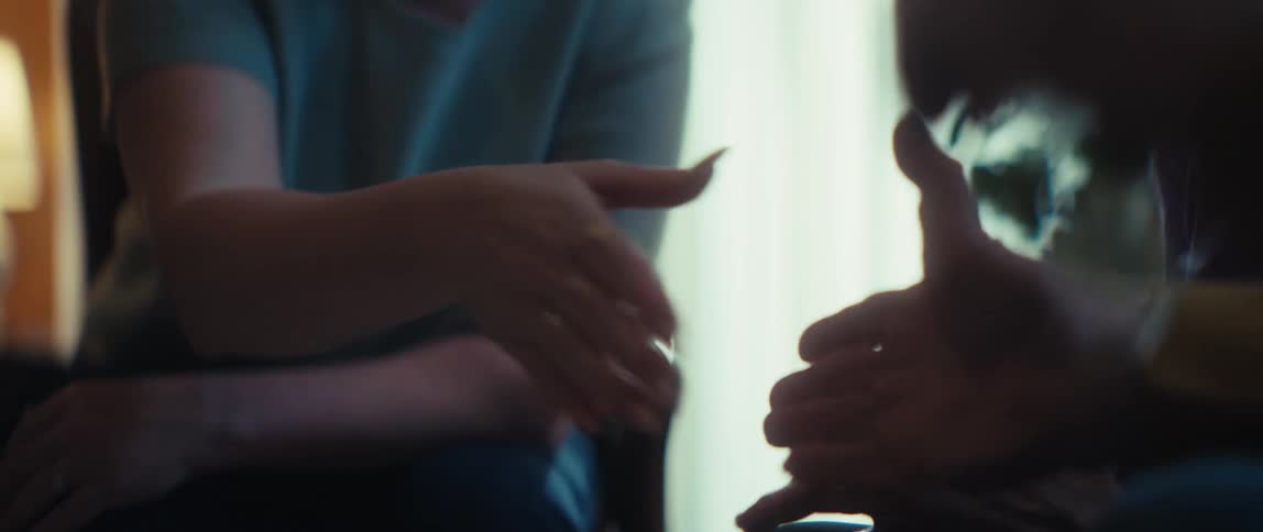 A woman reviews paperwork before shaking hands with a colleague, then smiles with relief after finalizing a successful deal