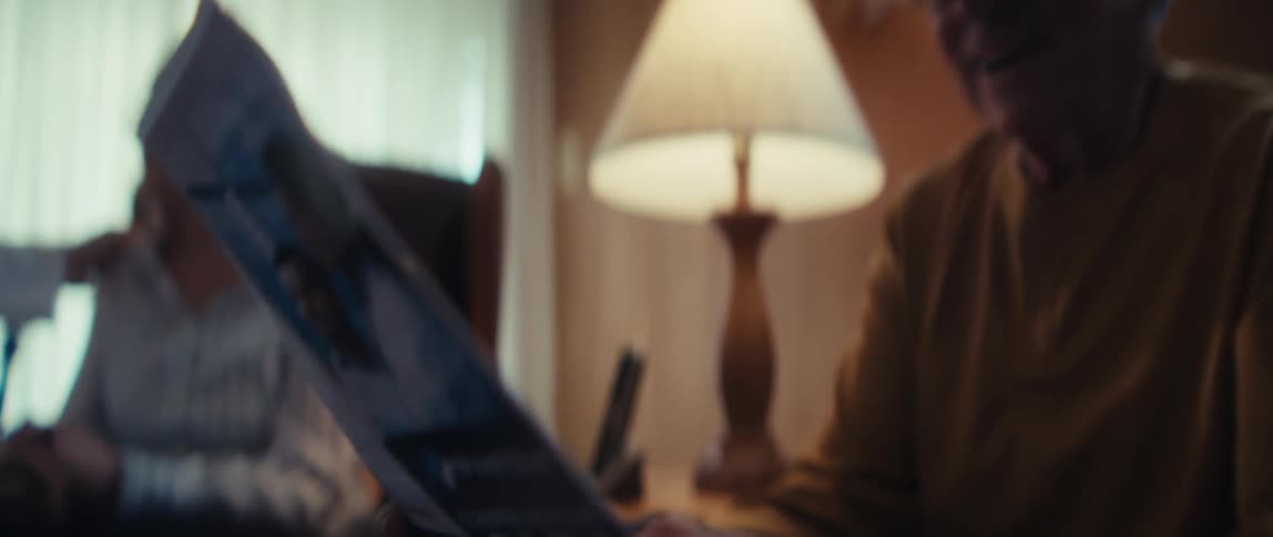 Elderly veteran smiles while reviewing a comprehensive healthcare brochure in his home with his wife